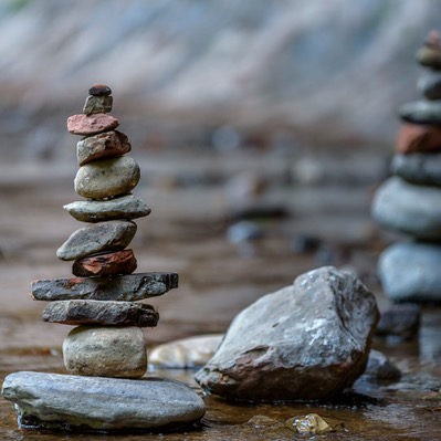 Balance and wellness concept. Close-up of river stones balanced in the shallow mountain creek. Low depth of field. Zen and spa inspired